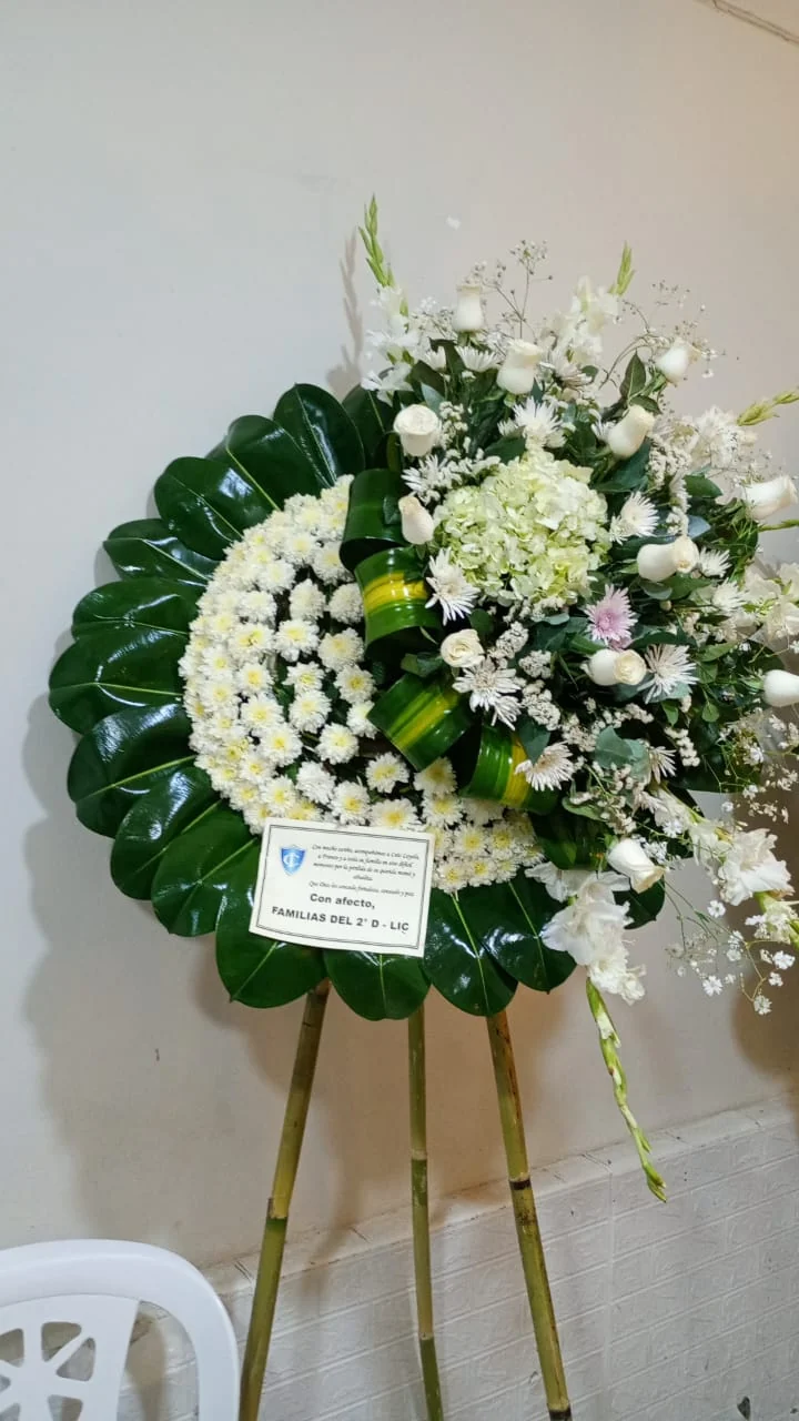 Arreglo floral blanco enviado por las familias del 2.º D, con una tarjeta del salón